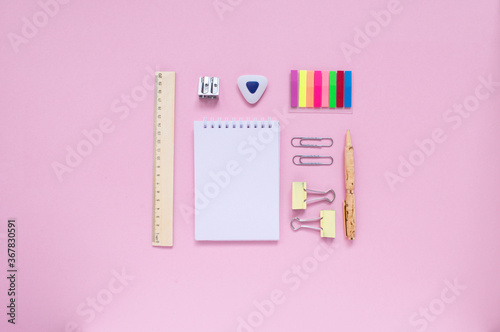 Stationary, back to school,creativity and education concept. Notebook, pen, pencil, eraser, ruler, paper clips, stapler, brush on pink background, flat lay