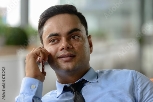 Young handsome Indian businessman in the city