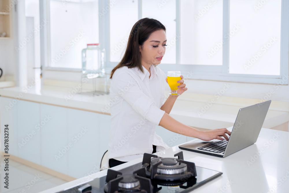 Woman works with laptop while drinks orange juice Woman works with laptop while drinks orange juice