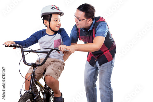 Young man teaches his boy to ride bike on studio