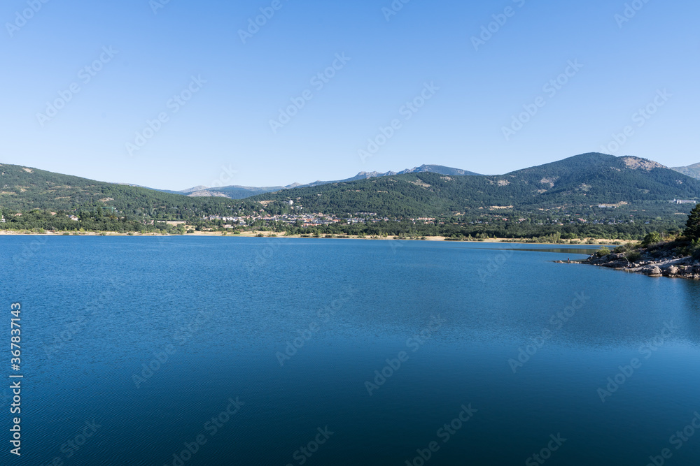 Lake from a reservoir surrounded by green mountains in Navacerrada
