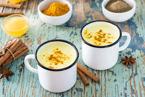 Detox drink. Golden milk with turmeric and cinnamon in mugs on a wooden table. Rustic style. Close-up