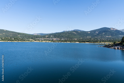Lake from a reservoir surrounded by green mountains in Navacerrada