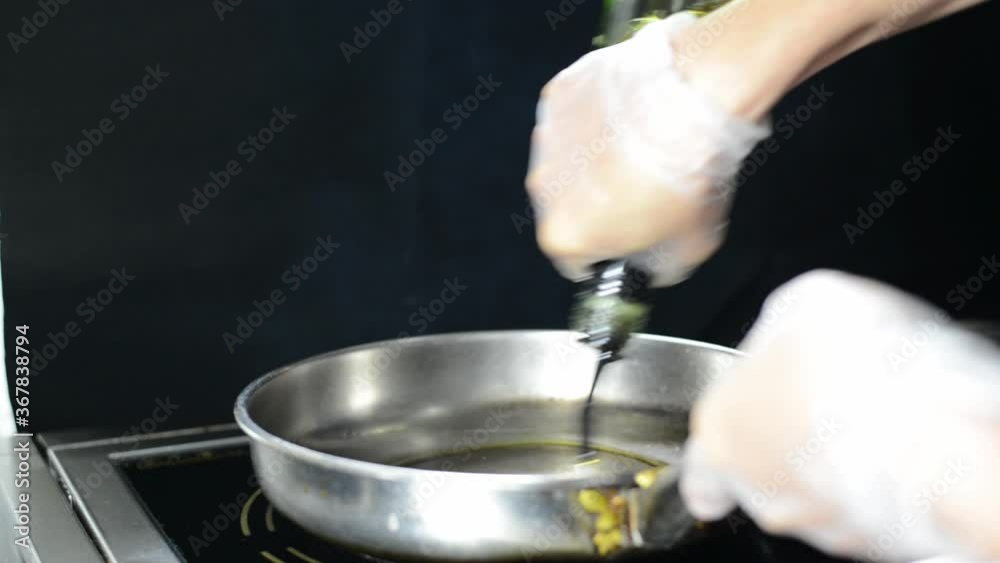 Chef pouring olive oil into hot saucepan on induction hob, slow motion Chef pouring olive oil into hot saucepan on induction hob, slow motion