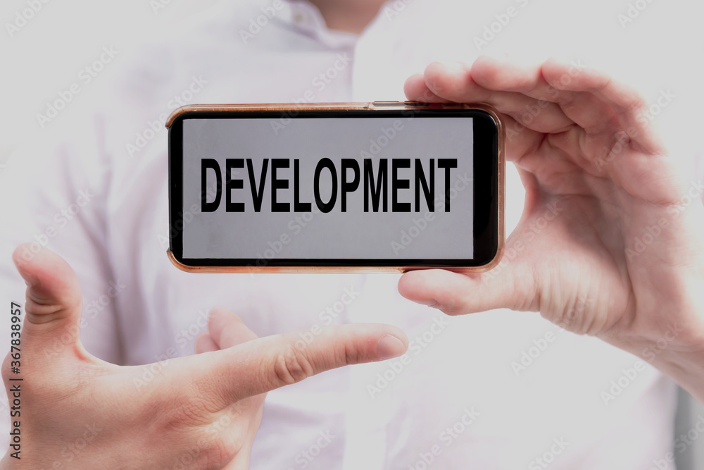 Word development on screen of smartphone in hands of businessman in white shirt. Business concept