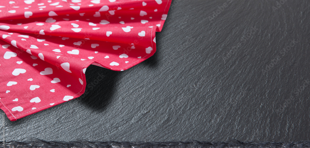 Fototapeta premium Red tablecloth, stone and slate on black background. Kitchen background.