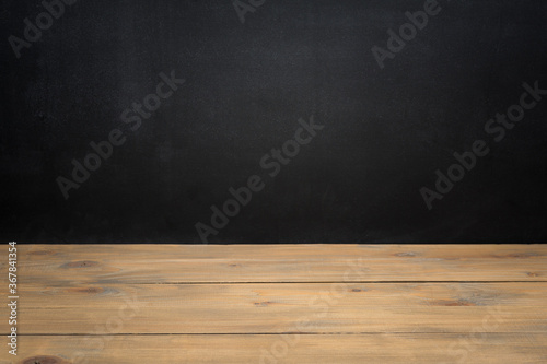 Empty wooden table over black textured chalkboard for product display