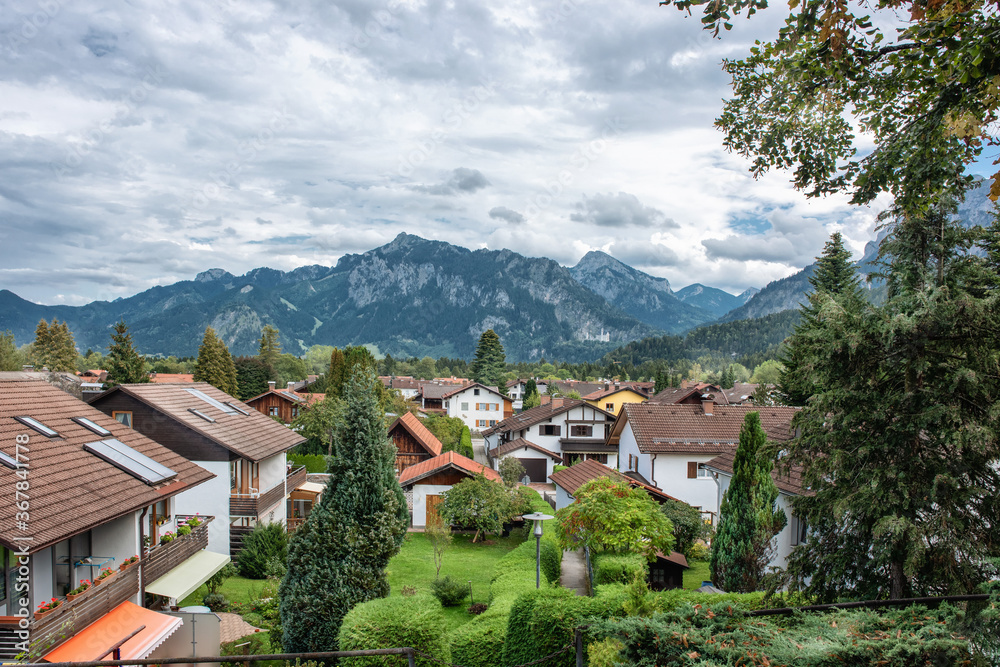 A great view of the Alps and an old German city in fall on background of mountains under dark cloudy sky.