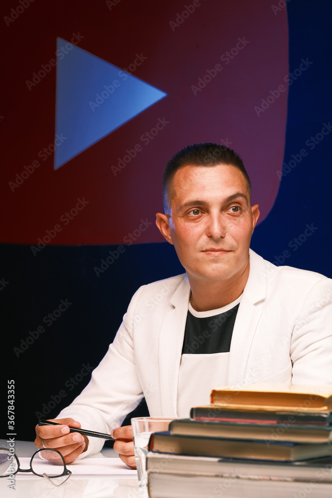 A young school teacher a man in a white jacket and glasses checks the homework of his students and prepare for a new lesson A young school teacher a man in a white jacket and glasses checks the homework of his students and prepare for a new lesson