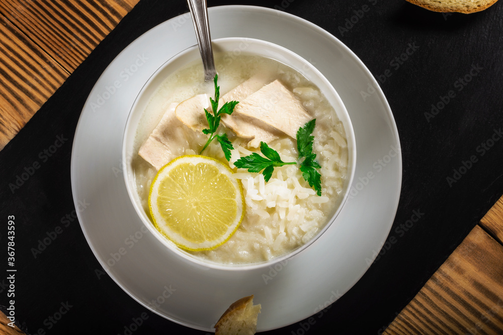 Chicken soup with lemon, egg yolks, parsley and rice. low key. Black background. Chicken soup with lemon, egg yolks, parsley and rice. low key. Black background.