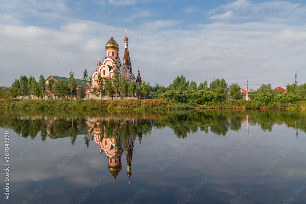 Russian orthodox church in Almaty, Kazakhstan known also as Church of Exaltation of the Holy cross, and its reflection in water.