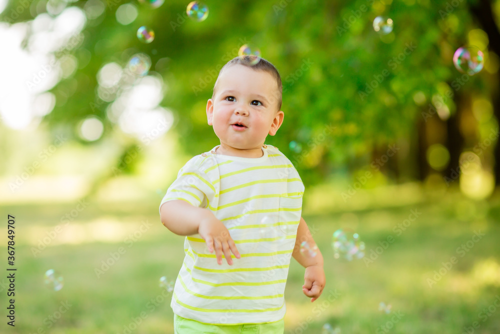 Happy baby boy one year plays with soap bubbles summer outdoors. Children's Lystyle Happy baby boy one year plays with soap bubbles summer outdoors. Children's Lystyle