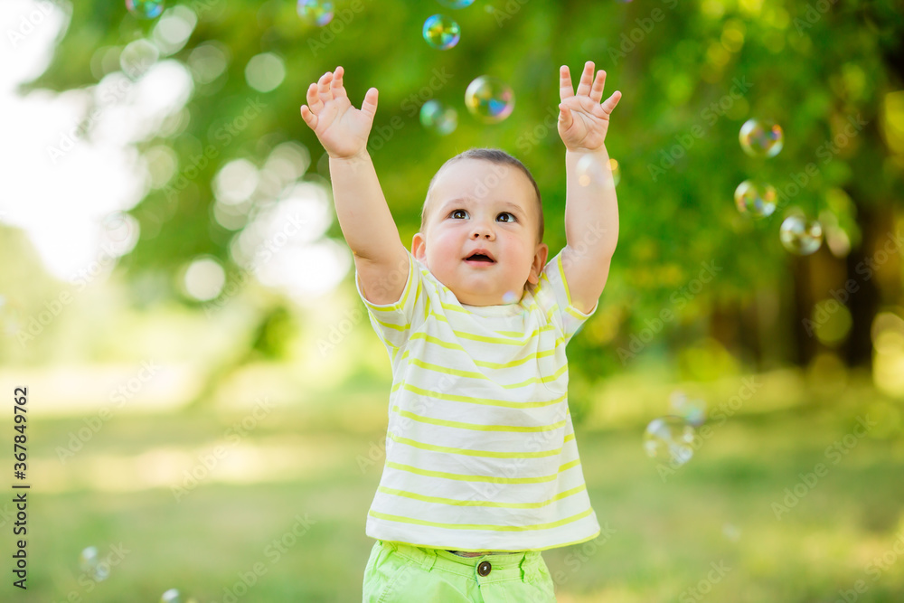 Happy baby boy one year plays with soap bubbles summer outdoors. Children's Lystyle Happy baby boy one year plays with soap bubbles summer outdoors. Children's Lystyle