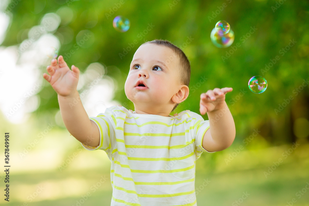 Happy baby boy one year plays with soap bubbles summer outdoors. Children's Lystyle Happy baby boy one year plays with soap bubbles summer outdoors. Children's Lystyle