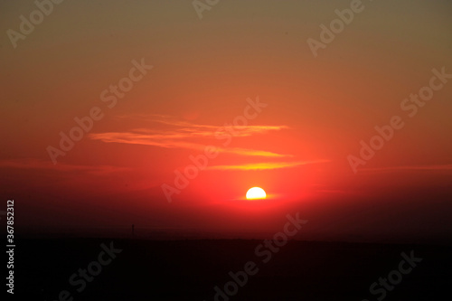 Red glow of the setting sun in the sky above the horizon © yanakoroleva27