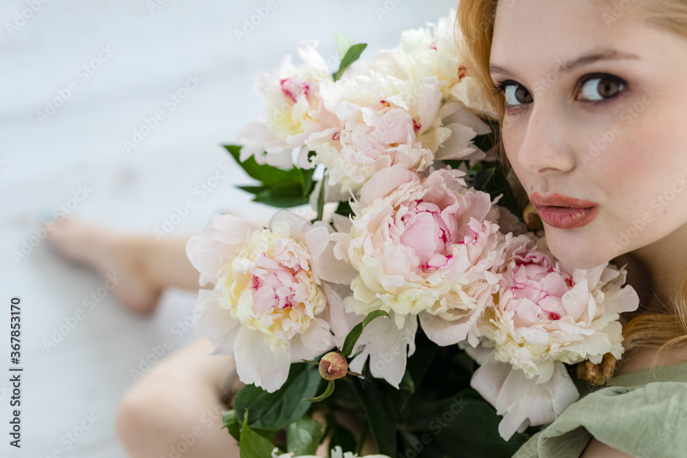 Naklejka premium beautiful sensual girl with long blonde hair in dress with a bouquet of pink peonies flowers. Сoncept of feminity