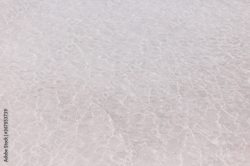 Crystal clear sea water and white sand. Small waves.
