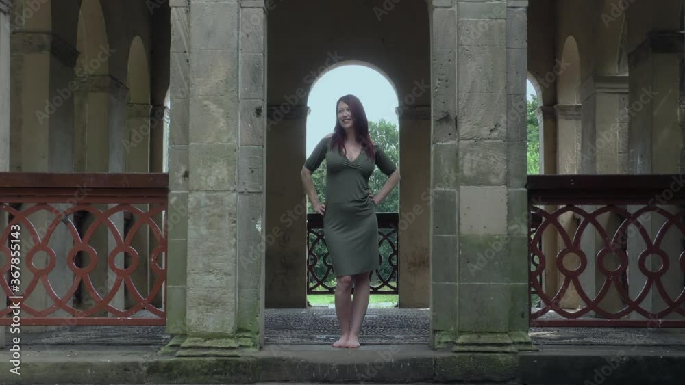 beautiful young lady posing and smiling playful in nature by stone columns beautiful young lady posing and smiling playful in nature by stone columns