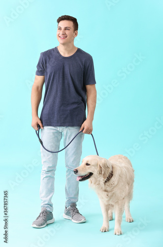Young man with cute dog on color background