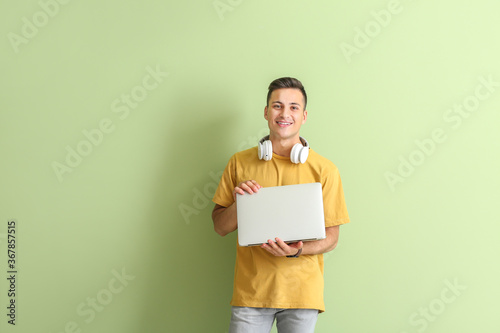 Male programmer with laptop on color background