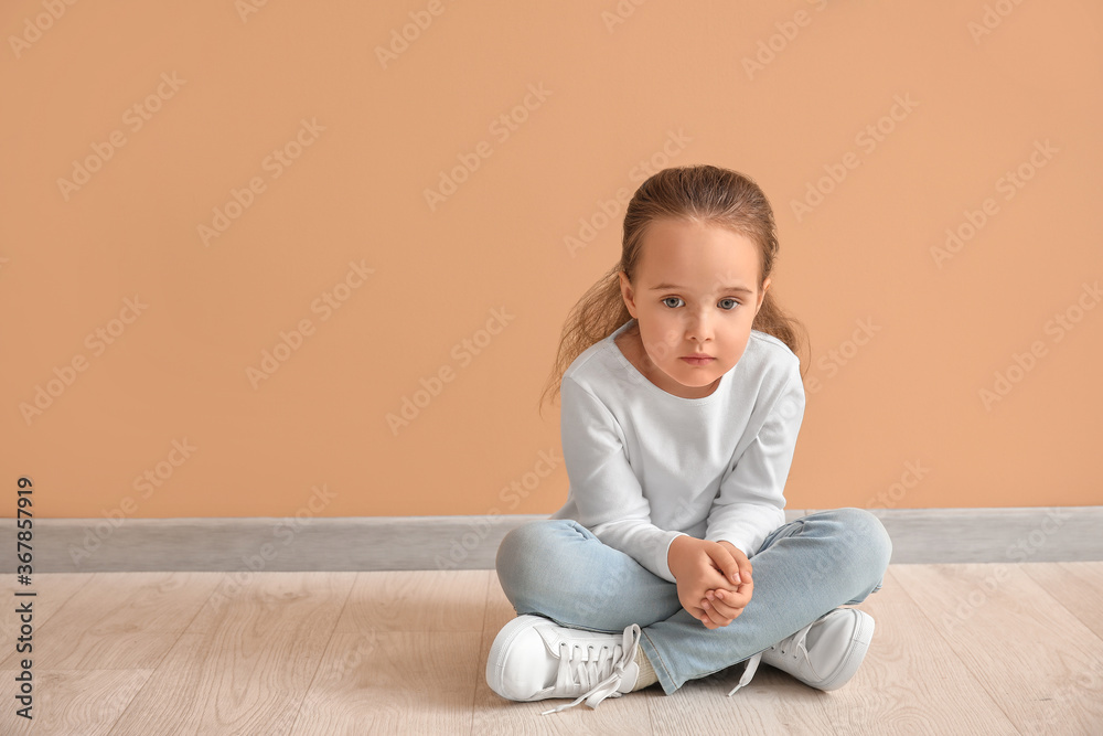 Sad little girl with autistic disorder sitting near color wall Sad little girl with autistic disorder sitting near color wall
