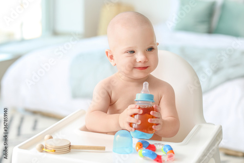 Cute little baby drinking juice from bottle at home