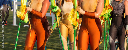 Marching band flag twirler.  woman dancer in costumes on a field with a marching band.