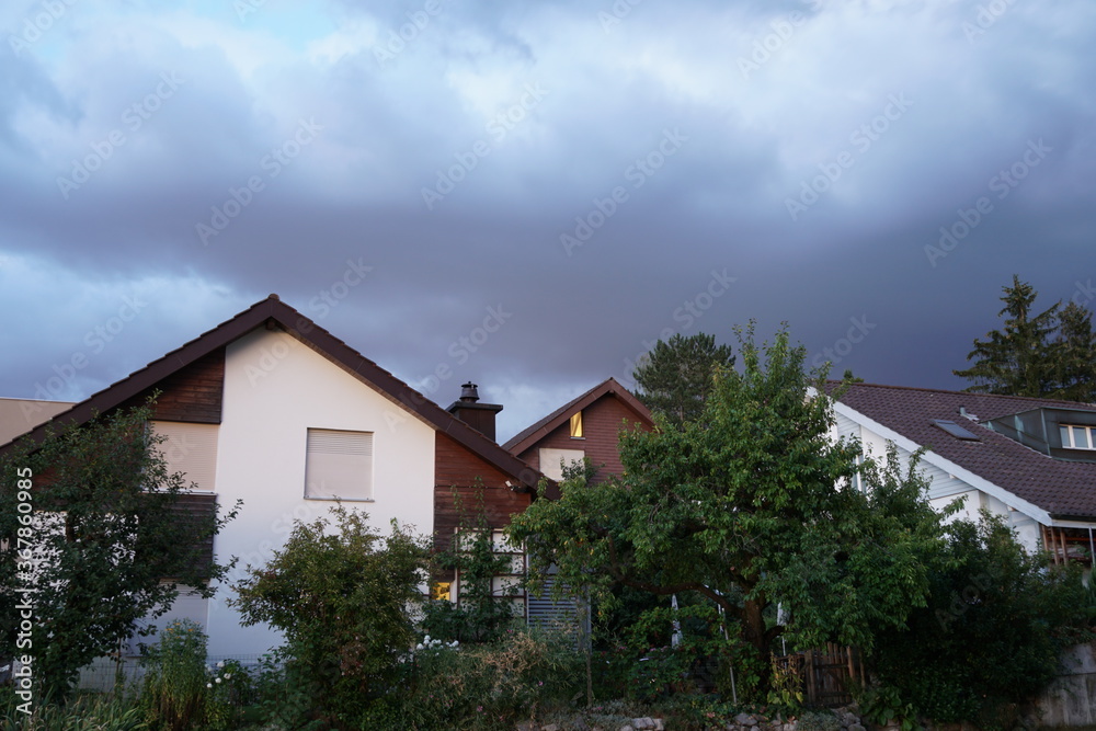 Storm heavy clouds swelling above peaceful residential quarter on a summer evening in Urdorf, Switzerland.