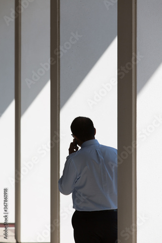 Rear view of businessman talking on mobile phone while standing between columns