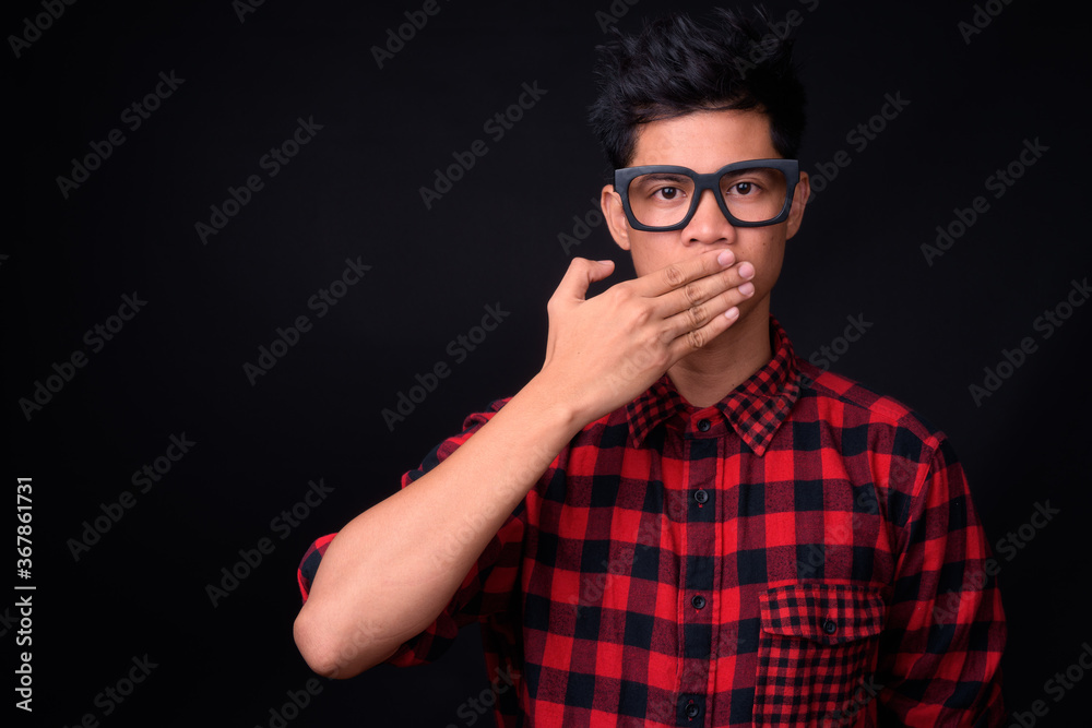 Portrait of young Asian hipster man against black background Portrait of young Asian hipster man against black background