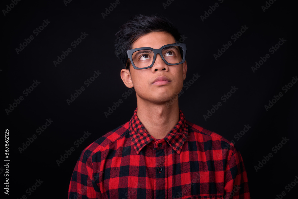Portrait of young Asian hipster man against black background Portrait of young Asian hipster man against black background