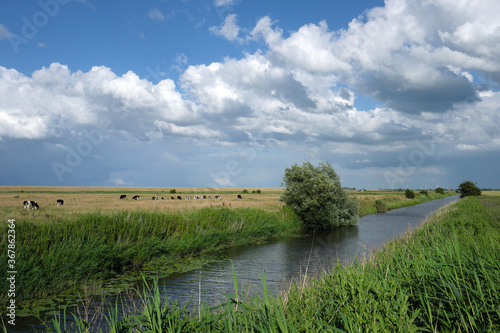 Ostfriesische Landschaft bei Dornumersiel in Niedersachsen mit Pumptief und starker Wolkenbildung mit blauem Himmel im Juni 2020 - Stockfoto