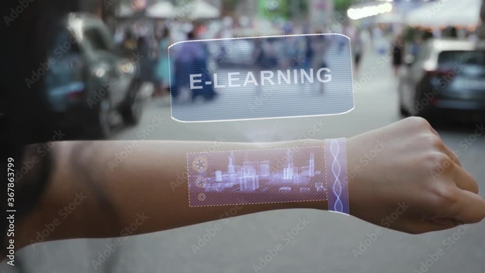 Female hand activates conceptual HUD holograms on smart bracelet with text E-learning. Unrecognizable woman with holographic technology on a city street background