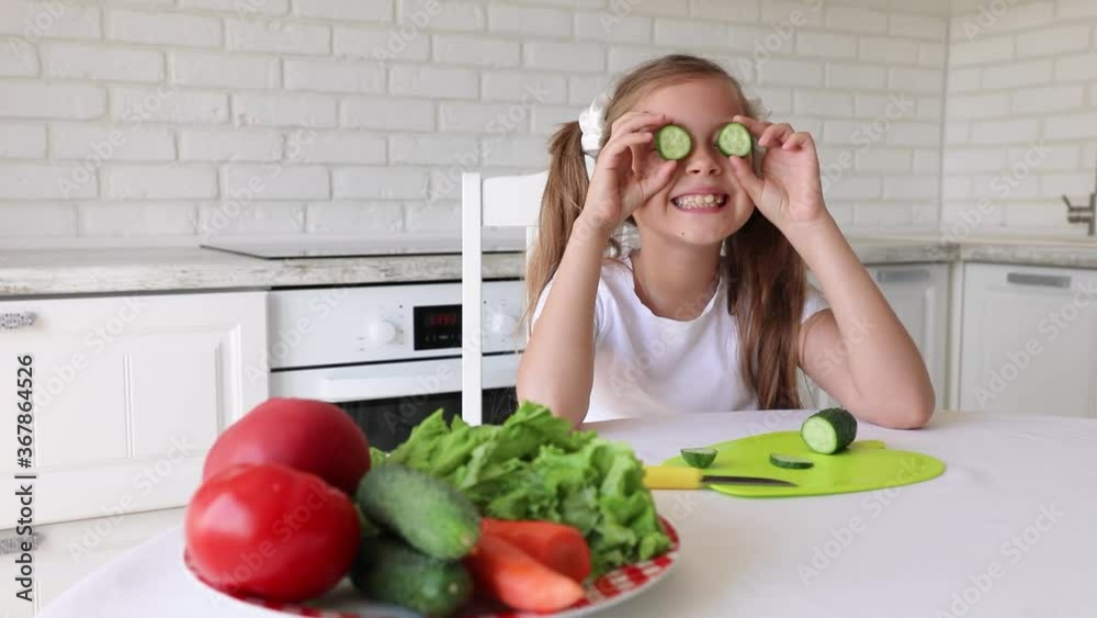 little girl cuts cucumber. Child Preparing Green Salad in Kitchen, Girl Cutting Vegetables Healthy Meal little girl cuts cucumber. Child Preparing Green Salad in Kitchen, Girl Cutting Vegetables Healthy Meal