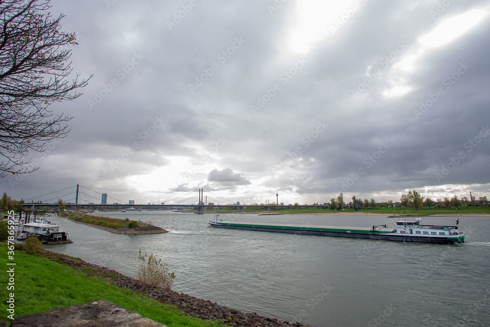 Amazing scene with Rhine river  and long vessel - dry cargo ship in Dusseldorf,  Germany. Autumn beginning 