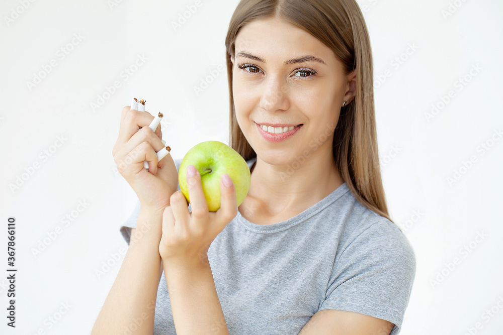 Stop smoking, woman holding a broken cigarette and a green apple Stop smoking, woman holding a broken cigarette and a green apple