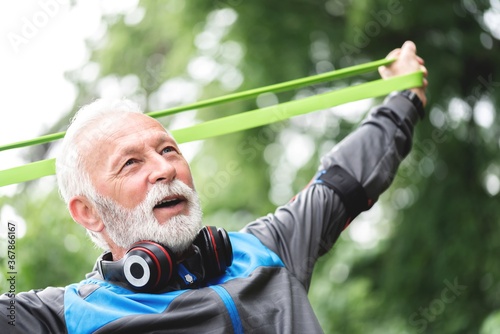 Senior sportsman exercising with resistance band at park
