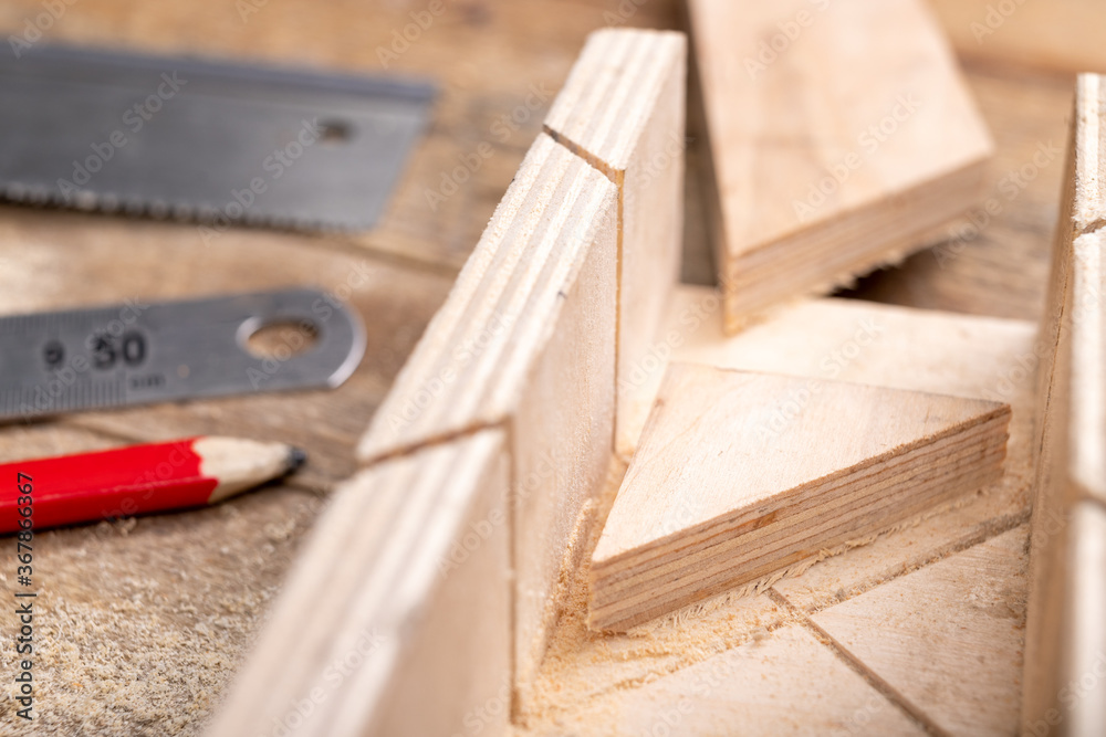 Cutting boards with a handsaw at an angle in the template. Minor carpentry work in the workshop. Light background. Cutting boards with a handsaw at an angle in the template. Minor carpentry work in the workshop. Light background.