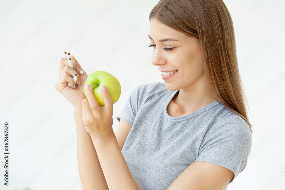 Stop smoking, woman holding a broken cigarette and a green apple Stop smoking, woman holding a broken cigarette and a green apple