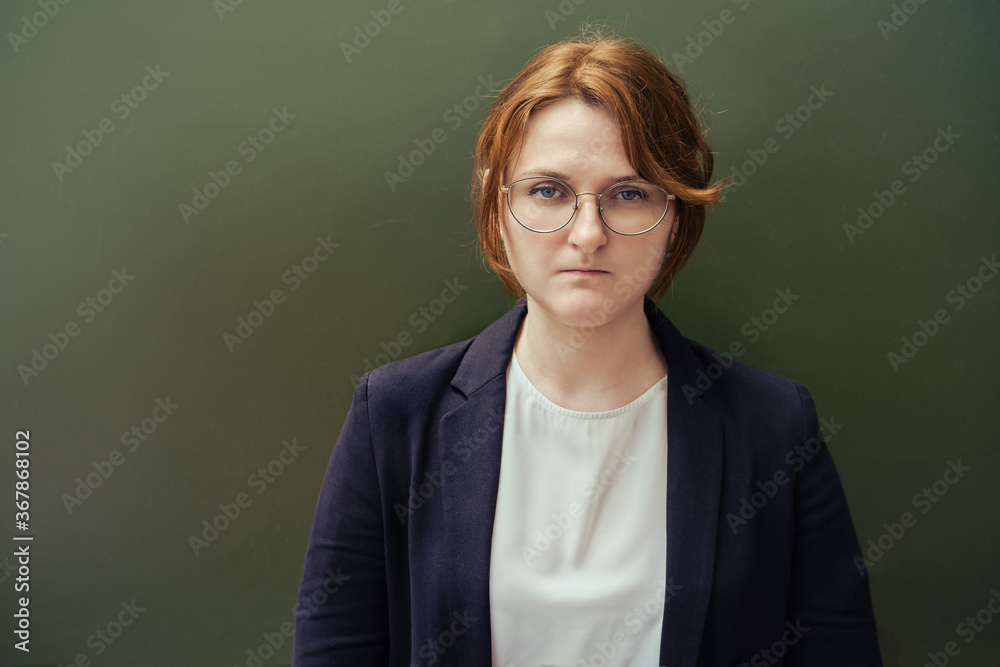Sad teacher in a suit at the blackboard, copy space. Female school teacher, close-up Sad teacher in a suit at the blackboard, copy space. Female school teacher, close-up
