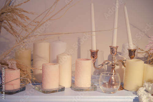 Vintage candles in a candlestick and flowers on the shelf, close-up