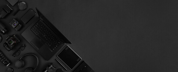 Top view of of photography gear and laptop geometricaly arranged on abstract black background