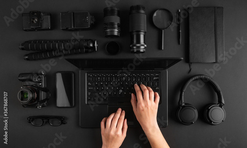 Top view of female hands working on laptop on minimal photographers desk