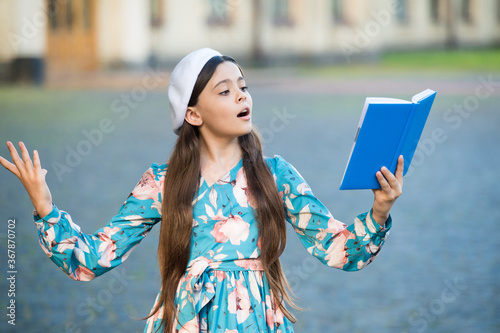 Girl student reading book outdoors, recite poetry concept photo