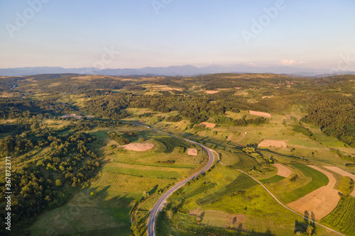Aerial view from above on the country road in mountain range in between green grass and trees around - nature travel concept drone photo on Tresibaba in Europe Serbia in sunny summer day
