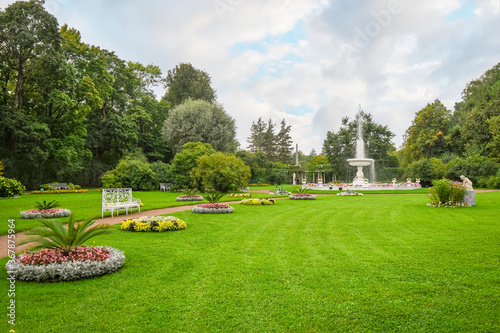 A peaceful garden with flowers, water fountain and bench near Catherine's Garden and Palace at Pushkin, Saint Petersburg, Russia.