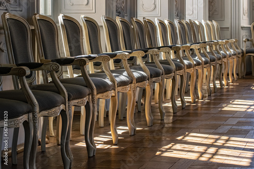Rows of elegant chairs in the palace hall. Brown wood and silk fabric upholstery.