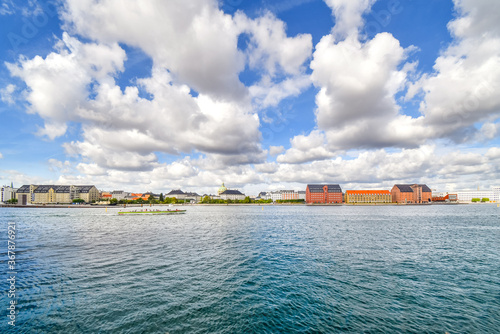 A tourist cruise boat floats past Amalienborg castle and the Marble or Frederik's Church on the water near Holmen Island harbor in Copenhagen Denmark. photo