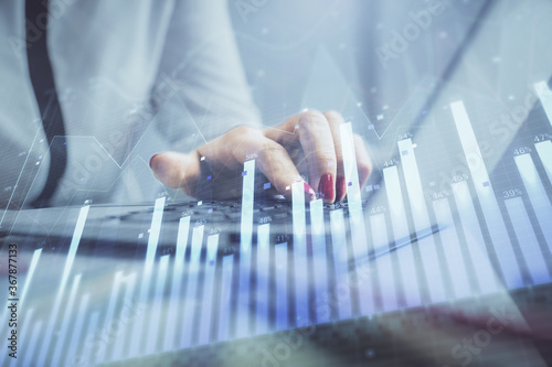 Double exposure of businesswoman hands typing on computer and financial graph hologram drawing. Stock market analysis concept.