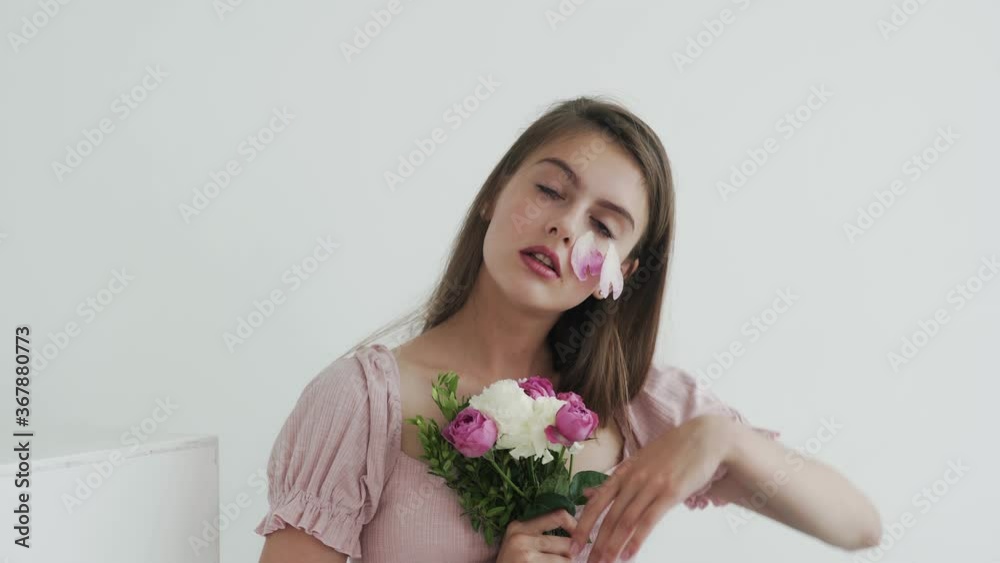 Attractive beautiful young woman model with flowers looking and posing at camera Attractive beautiful young woman model with flowers looking and posing at camera